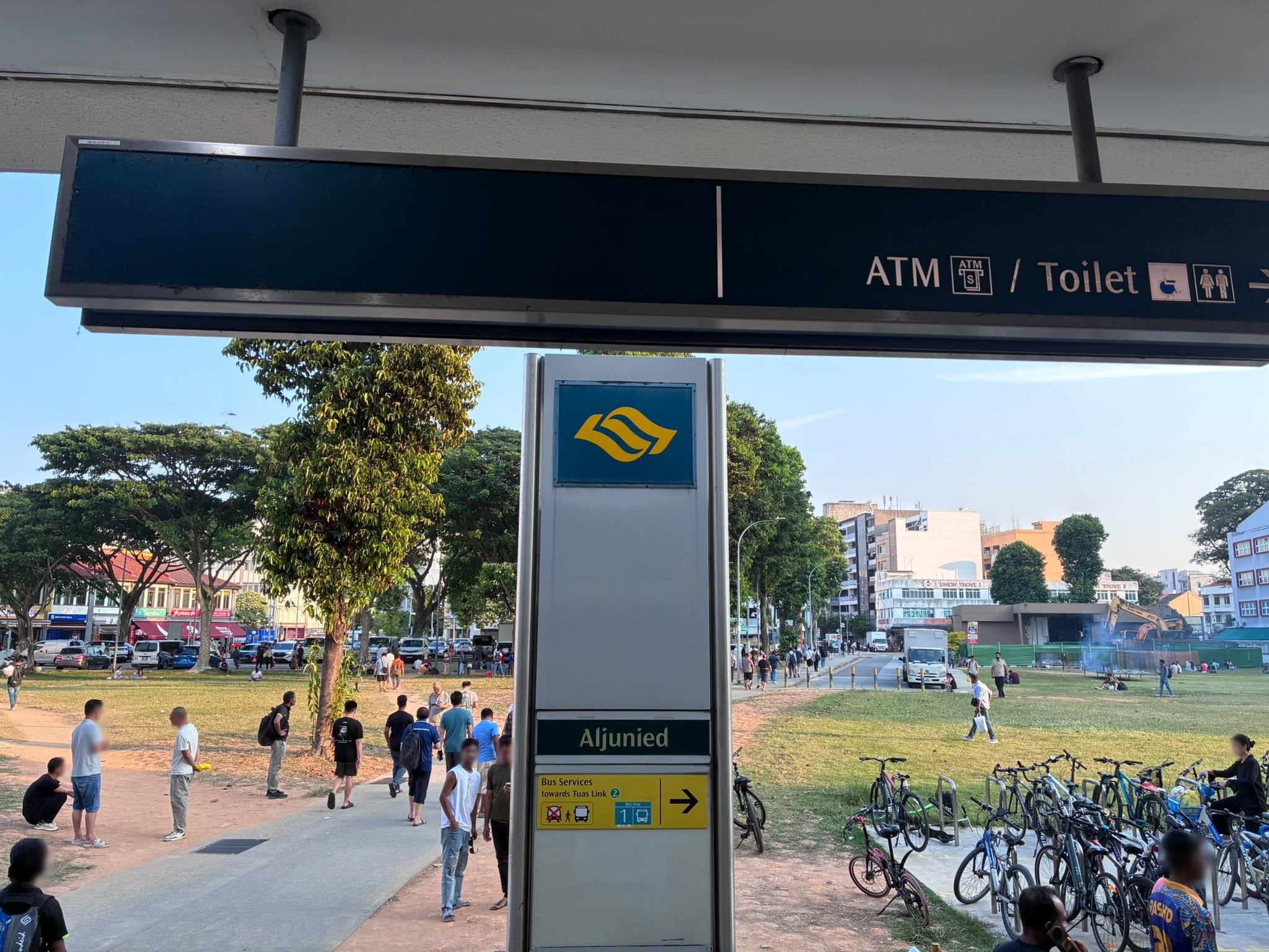 Bus stop and open field next to Aljunied MRT station, Singapore (faces blurred)