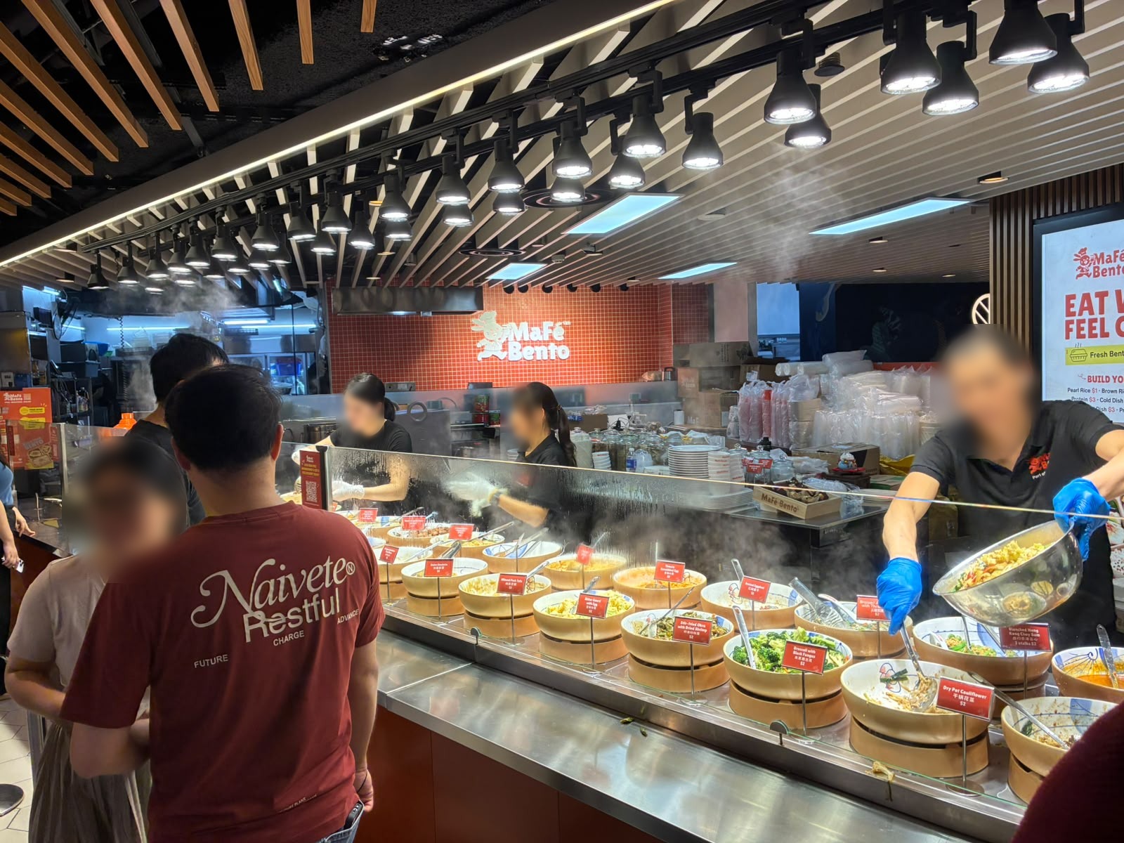 MaFe Bento counter with steam trays of dishes at The Basement food hall, Singapore (faces blurred)