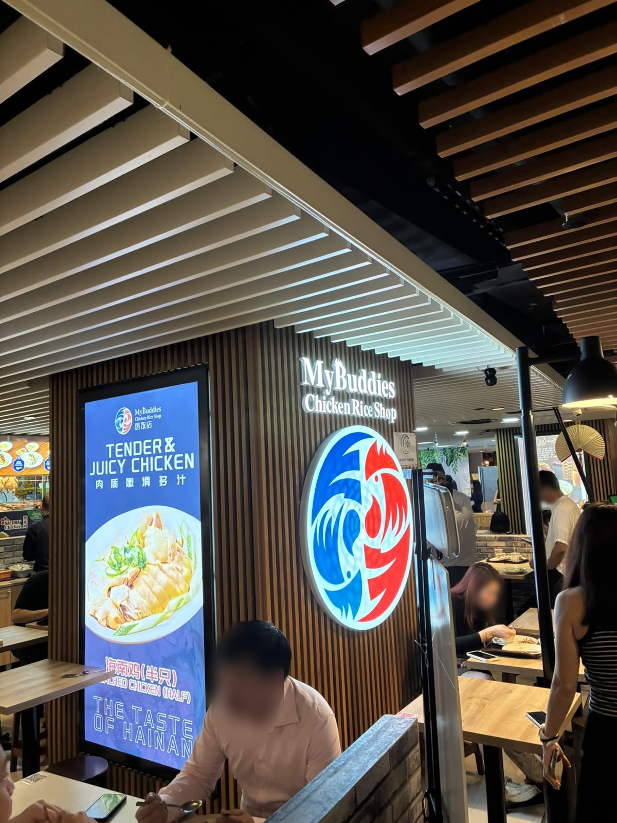 My Buddies Chicken Rice Shop signage and seating at The Basement, Singapore (faces blurred)