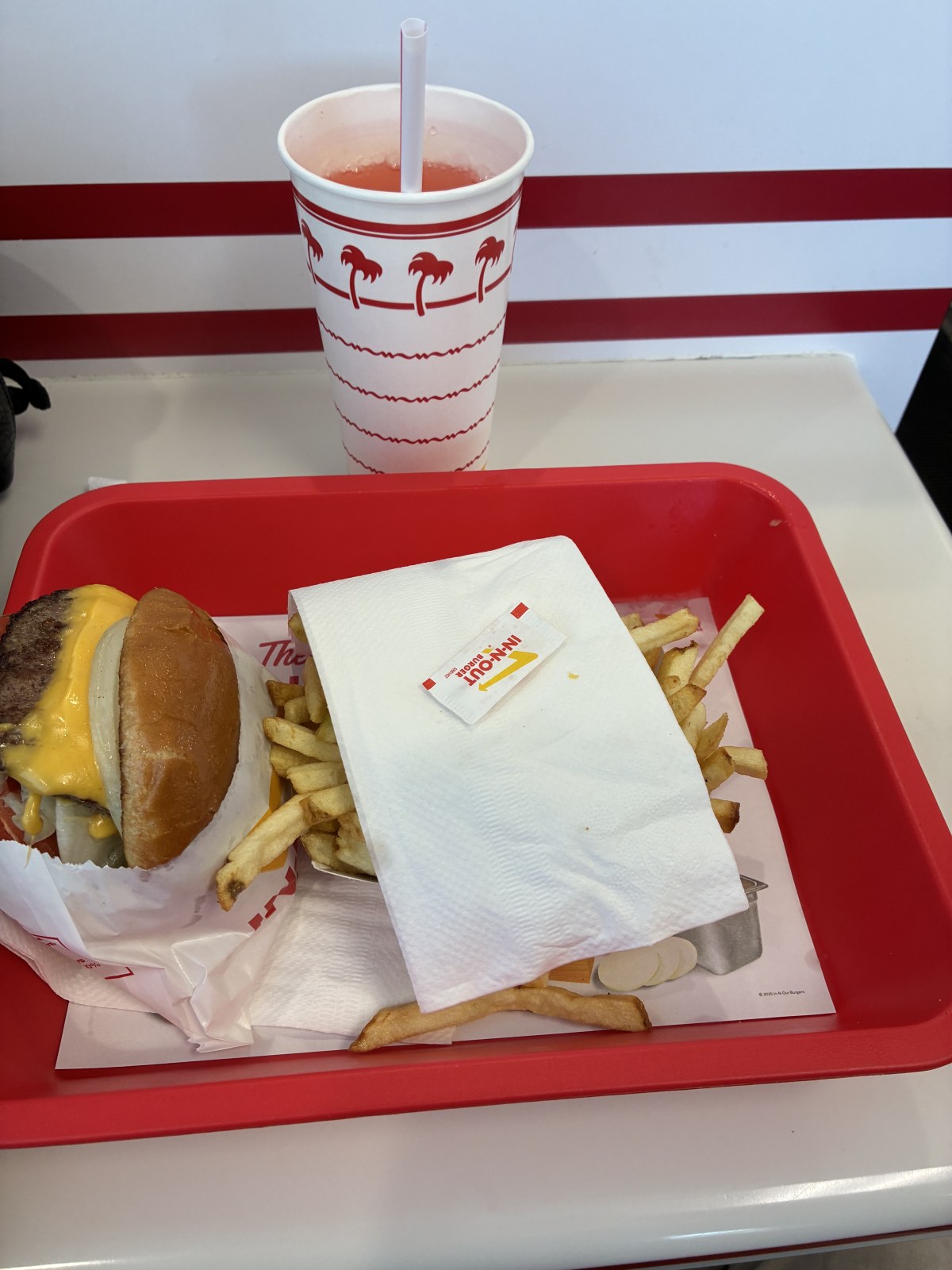 In-N-Out Burger cheeseburger, fries and pink lemonade on a red tray in Ontario, California