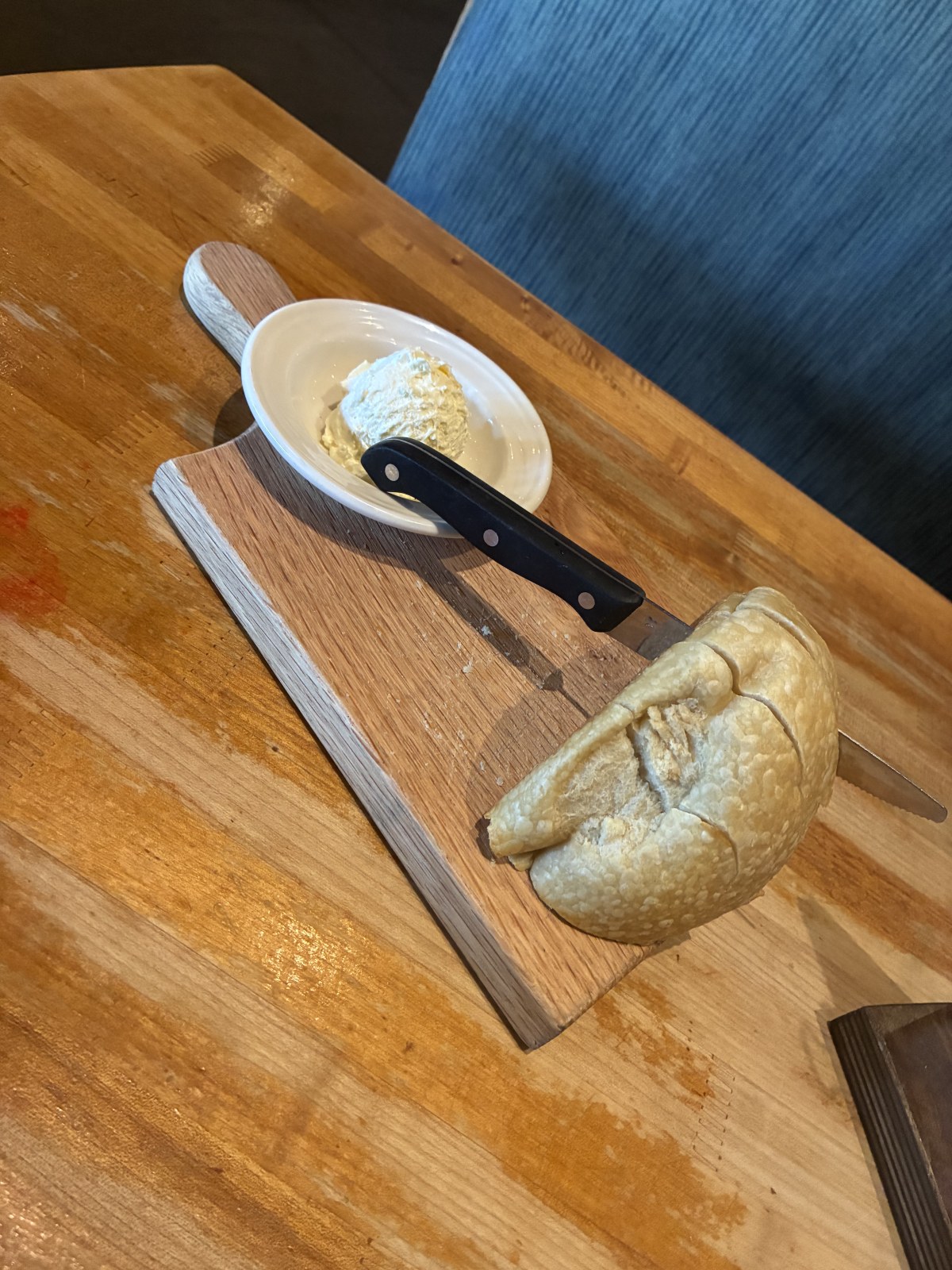 Warm sourdough loaf served on a wooden board with butter at Market Broiler, Ontario Mills