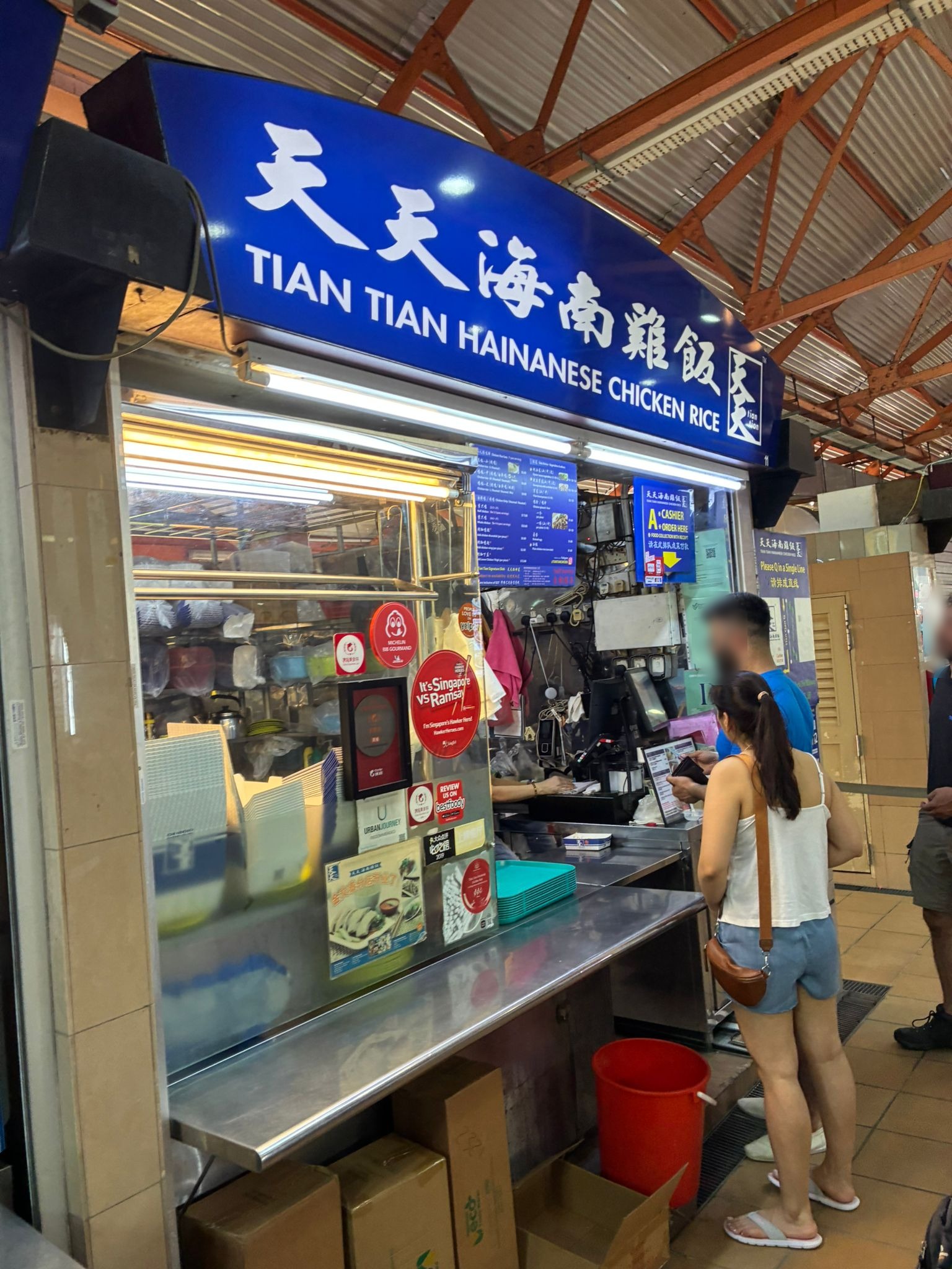 Cashier counter of Tian Tian Hainanese Chicken Rice with customers ordering (faces blurred)