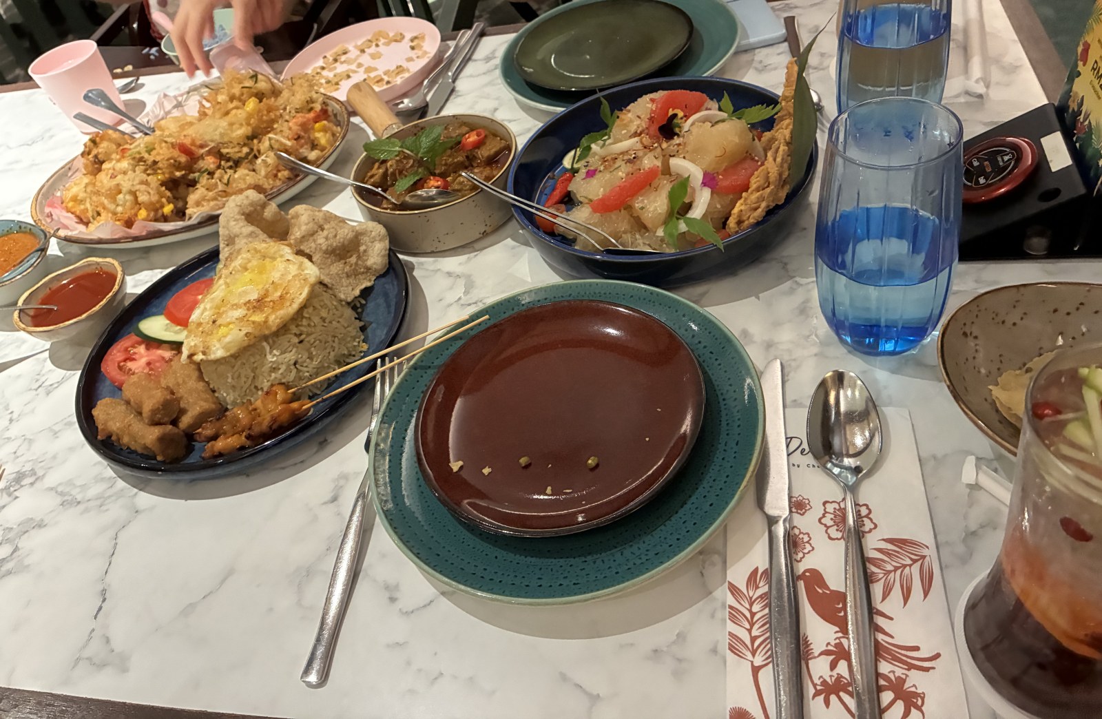 Table spread of Malaysian dishes including nasi lemak, calamari and pomelo salad at De.Wan 1958, Kuala Lumpur
