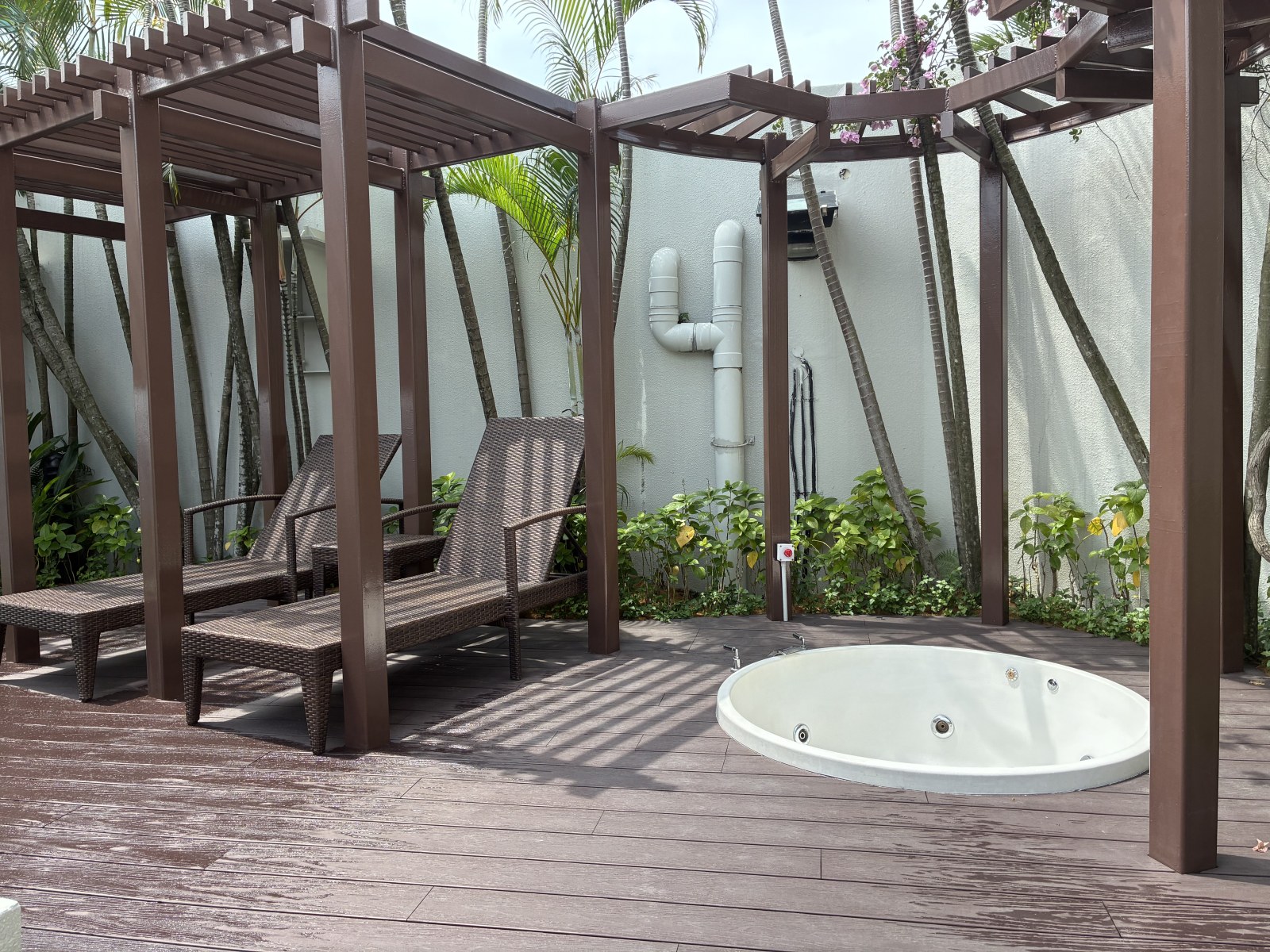 Private terrace of an executive suite with wooden pergola, sun loungers and a round jacuzzi at Hilton Kuala Lumpur, Malaysia