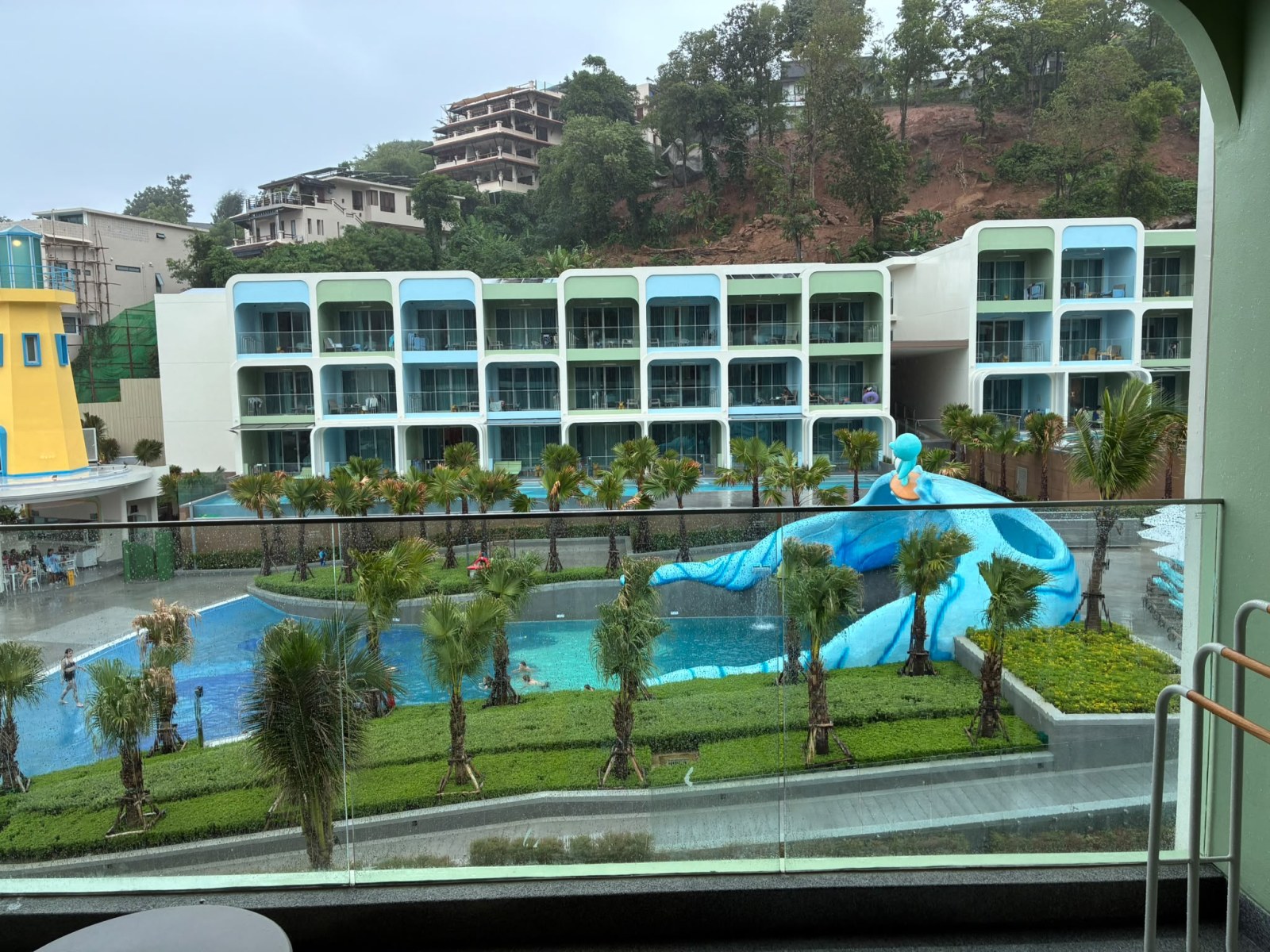 Kids pool with a blue water slide and wave pool at Katathani Phuket Beach Resort under cloudy sky, Thailand