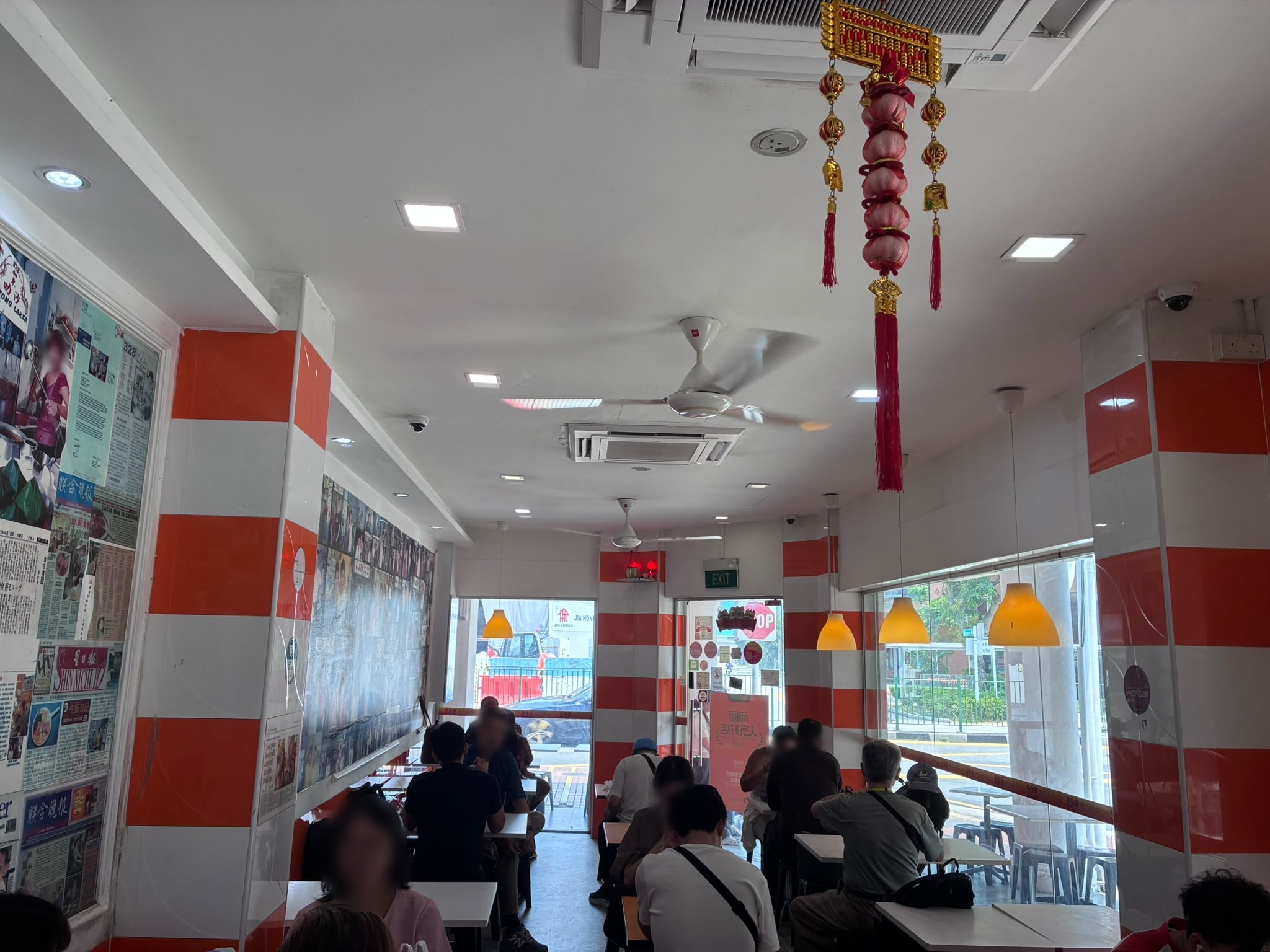 Inside 328 Katong Laksa with orange and white walls, Singapore (faces blurred)