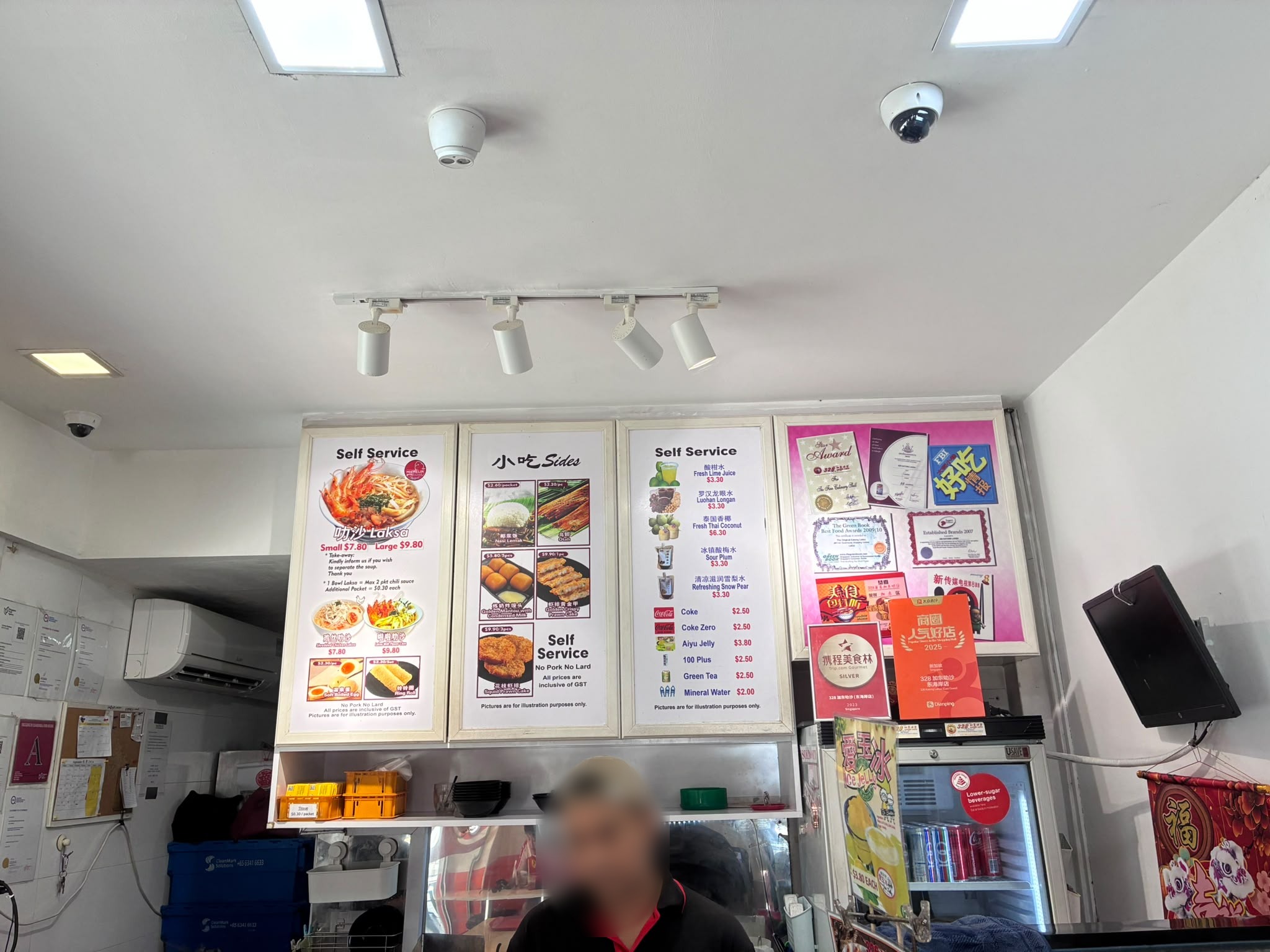 Menu board at 328 Katong Laksa showing small and large laksa prices (faces blurred)