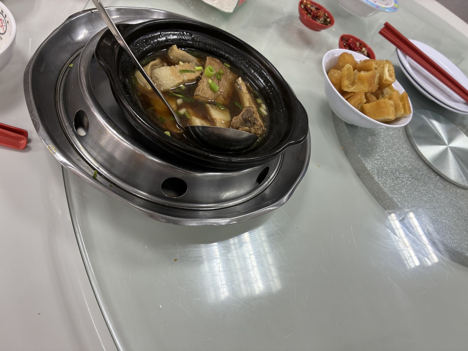 Claypot of dark soy-based bak kut teh with pork ribs and a bowl of fried dough sticks, Kuala Lumpur, Malaysia