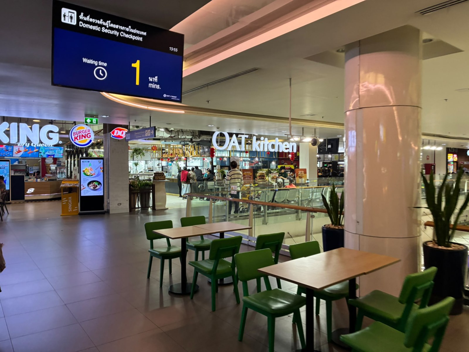 Domestic terminal of Phuket International Airport with food outlets and a security checkpoint wait time display, Thailand (faces blurred)