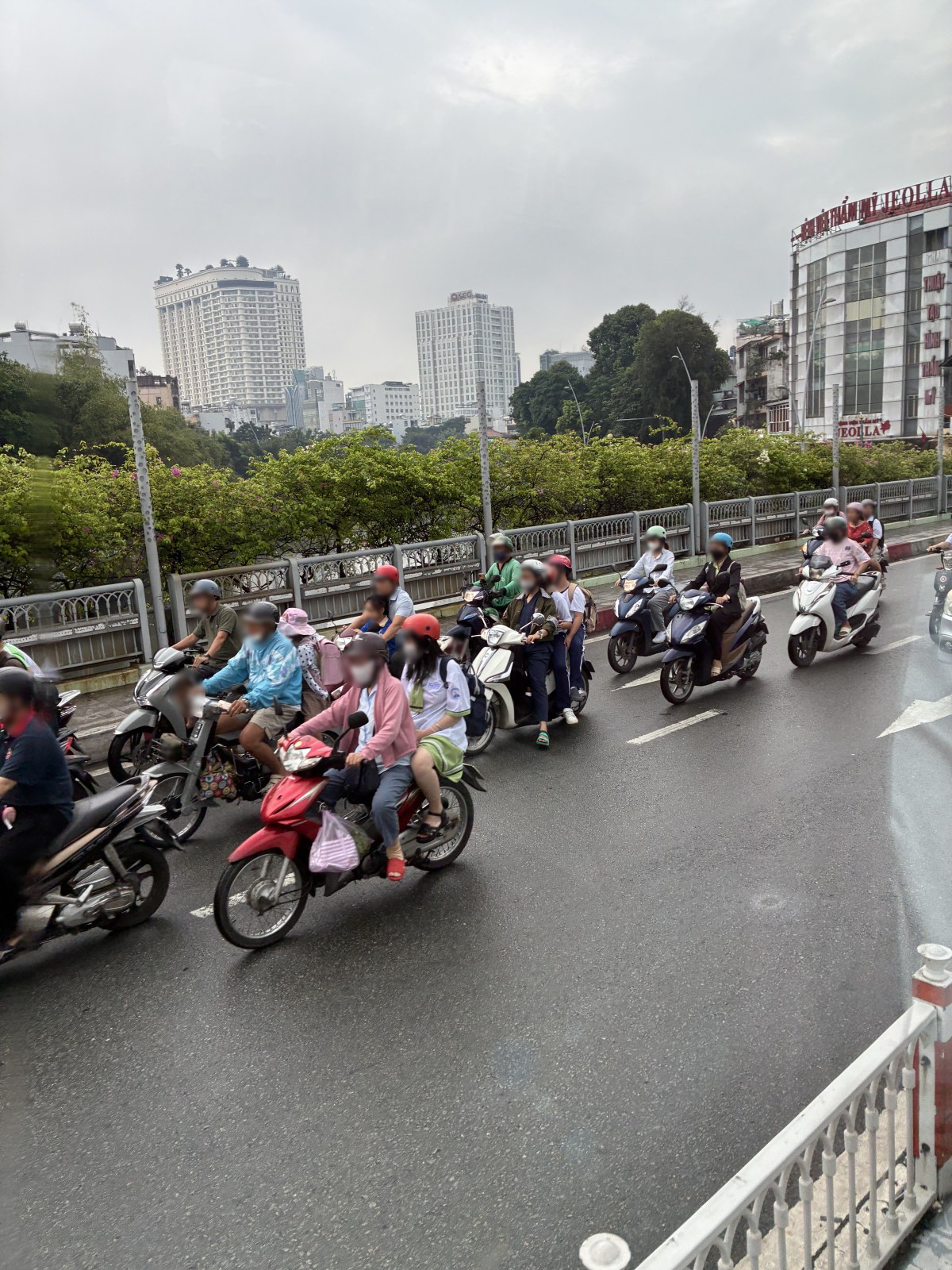 Motorbike traffic on a bridge in Ho Chi Minh City with the city skyline behind, Vietnam (faces blurred)
