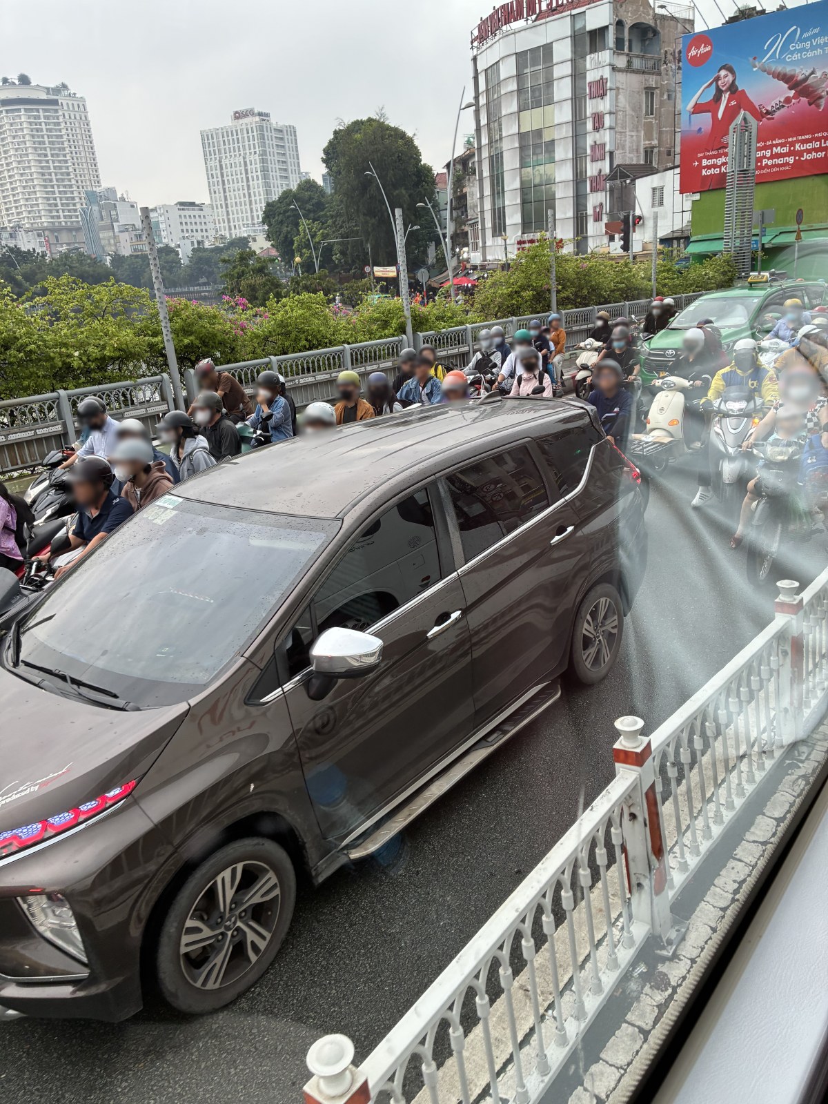 A car surrounded by motorbikes in heavy traffic in Ho Chi Minh City, Vietnam (faces blurred)