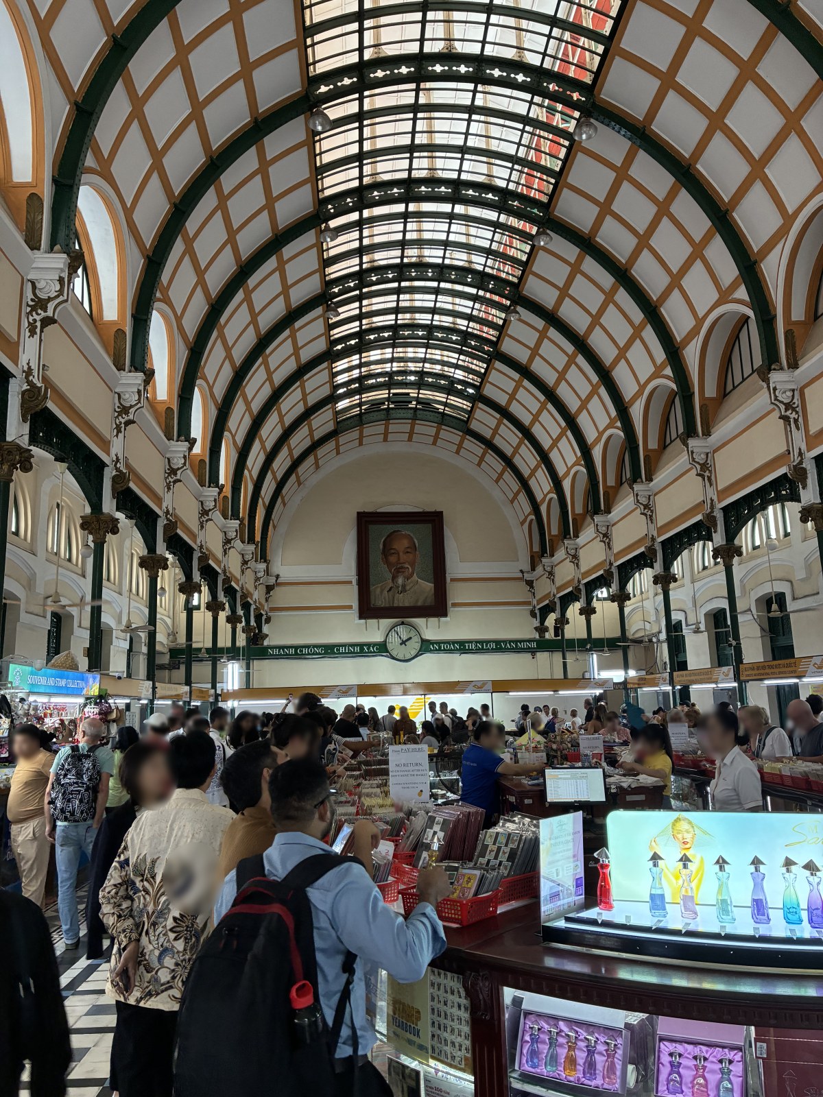 Vaulted interior hall of Saigon Central Post Office with souvenir counters, Vietnam (faces blurred)