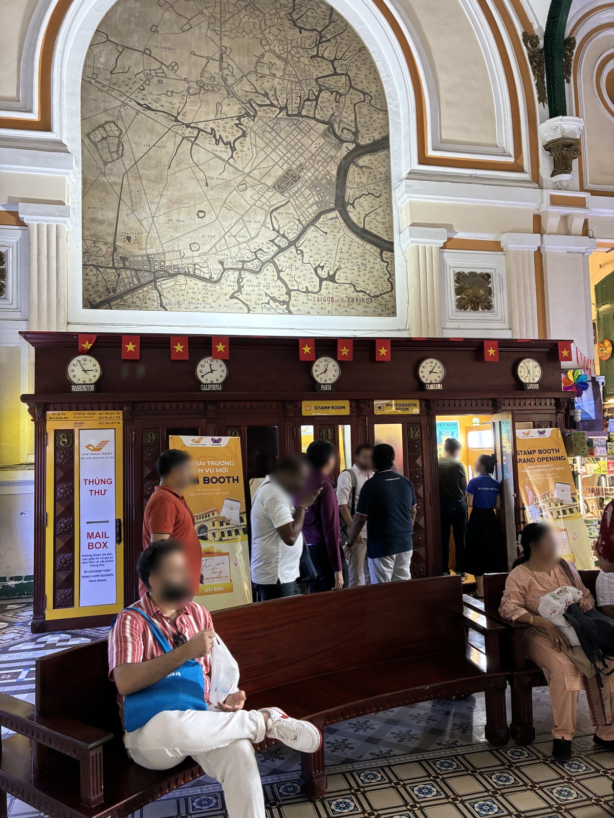 Old map of Saigon and its environs above wooden booths inside Saigon Central Post Office, Vietnam (faces blurred)
