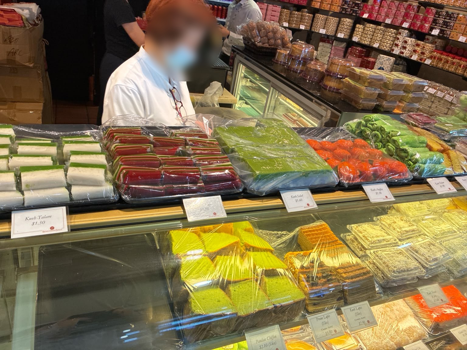 Nyonya kueh and pandan chiffon cake in the Bengawan Solo display case (faces blurred)
